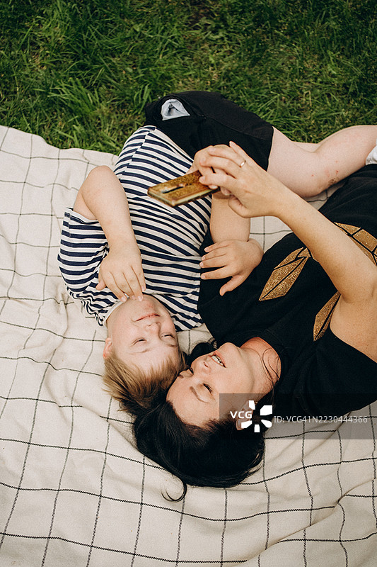 母亲和患有唐氏综合症的儿子在毯子上放松，享受珍贵的时光。图片素材