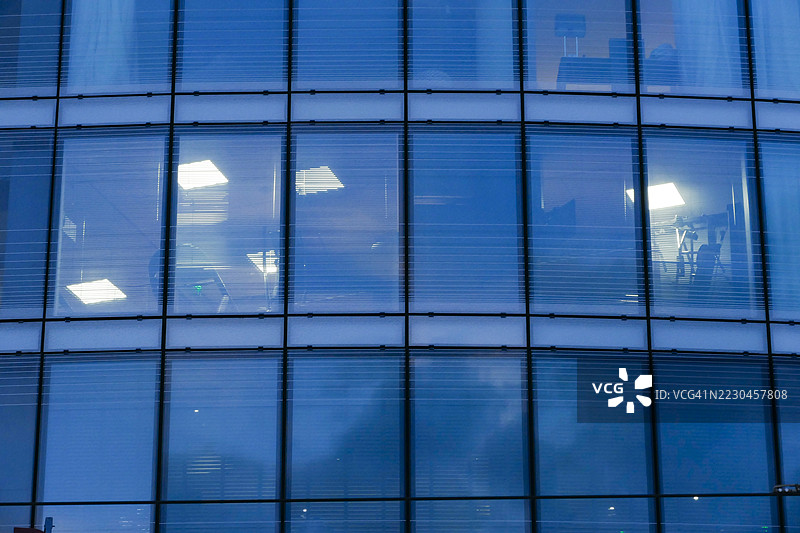现代建筑的正面视图，夜间有一些办公室在工作图片素材