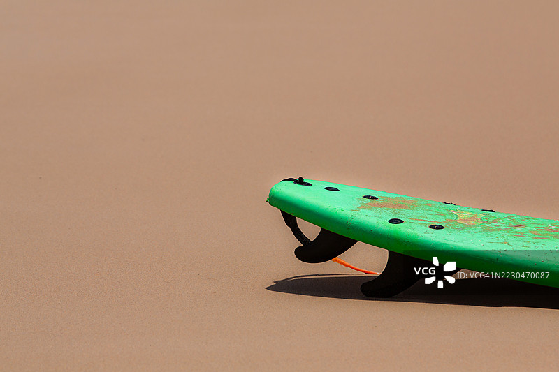 橙色沙滩上的绿色冲浪板，留有充足的空白区域供文字使用图片素材