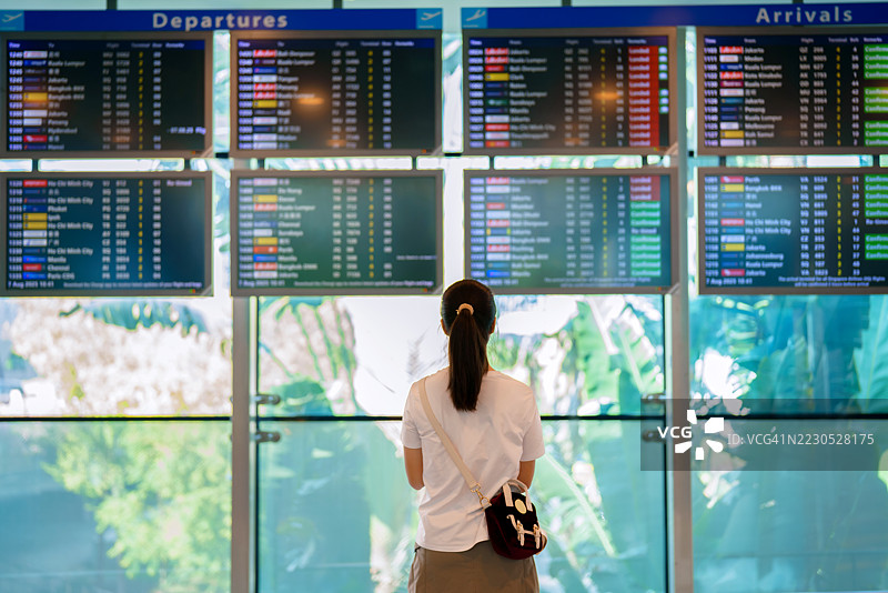 亚洲少女在机场候机厅查看航班信息显示屏图片素材