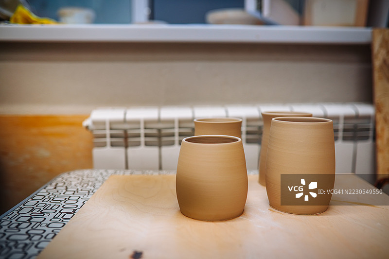 陶艺工作室中，经过烧制的杯子摆放在桌子上。图片素材