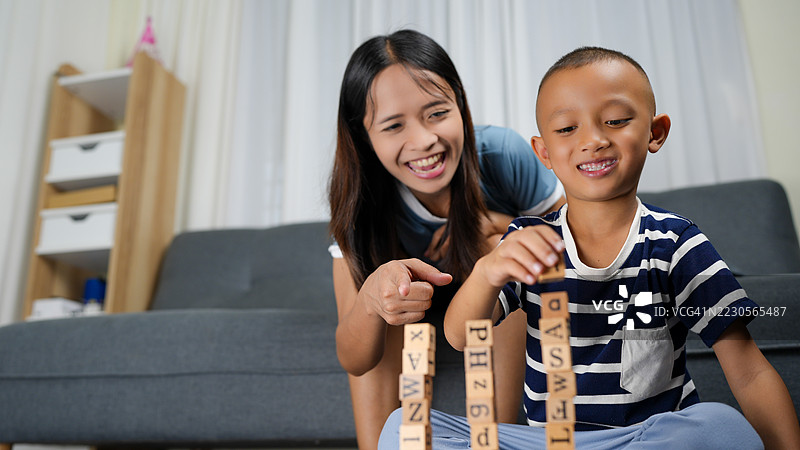 妈妈和儿子在温馨的客厅里一起玩耍，享受着木块带来的乐趣，培养创造力并增进亲子关系。图片素材