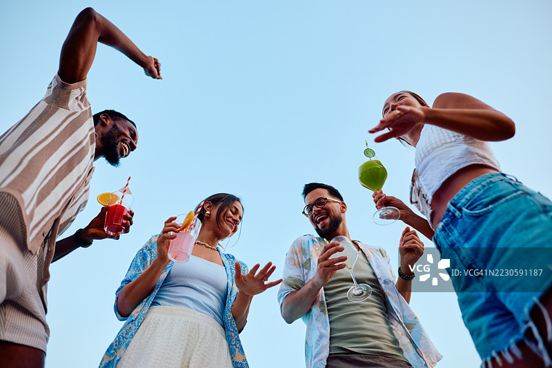 一群朋友在夏季派对上跳舞和喝鸡尾酒图片素材