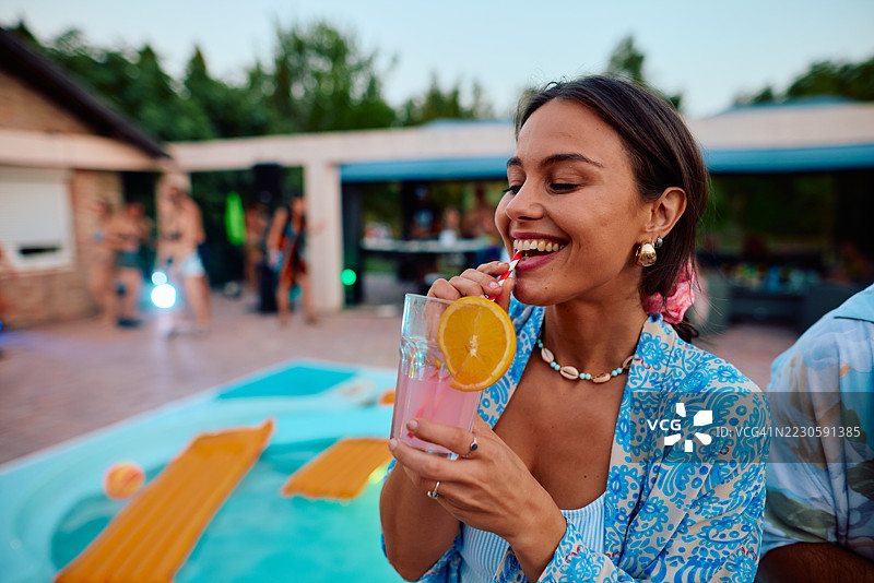 年轻女性在泳池派对上享受鸡尾酒图片素材