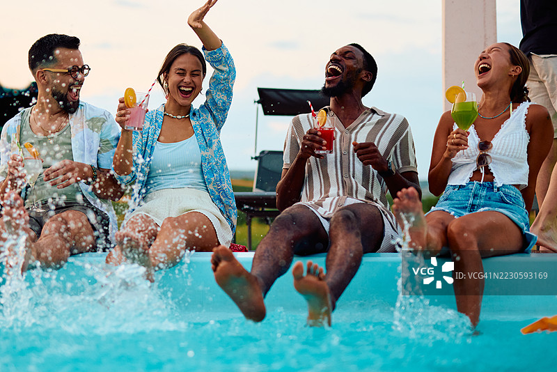 年轻朋友们在泳池中享受鸡尾酒和嬉水图片素材