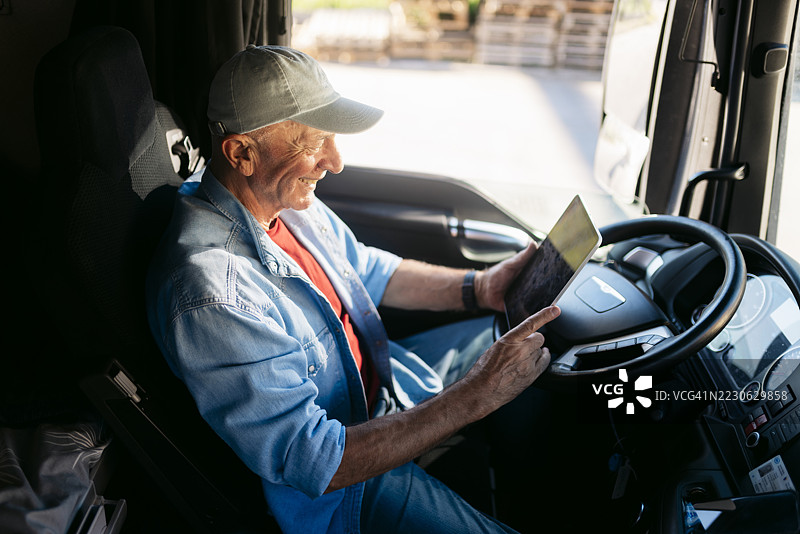 资深卡车司机在卡车内使用数字平板电脑图片素材