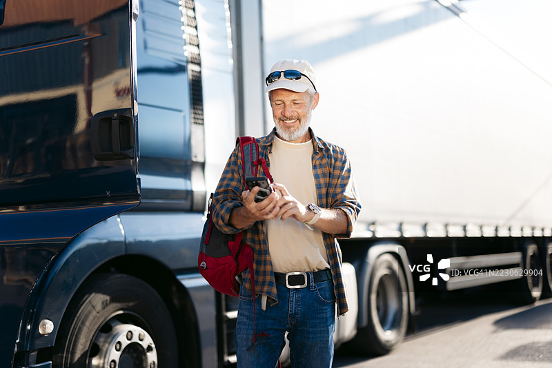 卡车司机在卡车旁使用智能手机应用程序图片素材