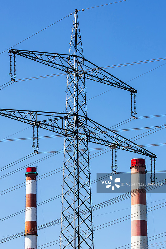 电力塔与两座高烟囱在蓝天背景下图片素材