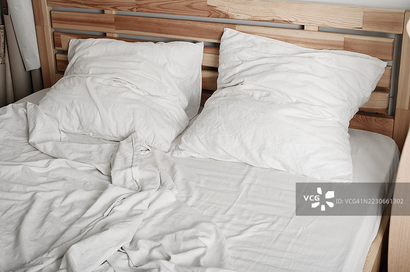 未整理的床铺，白色床单和木质床头板 - 舒适的早晨氛围图片素材