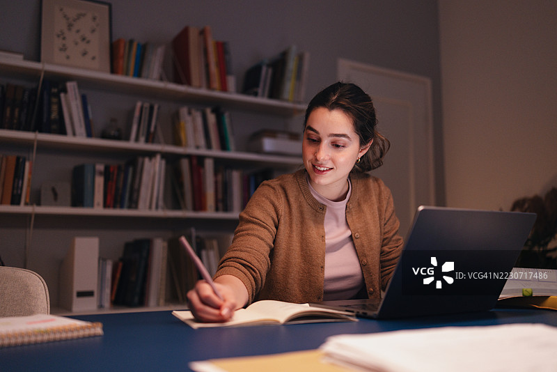 学生在舒适的图书馆书桌上用笔记本电脑和书籍学习图片素材