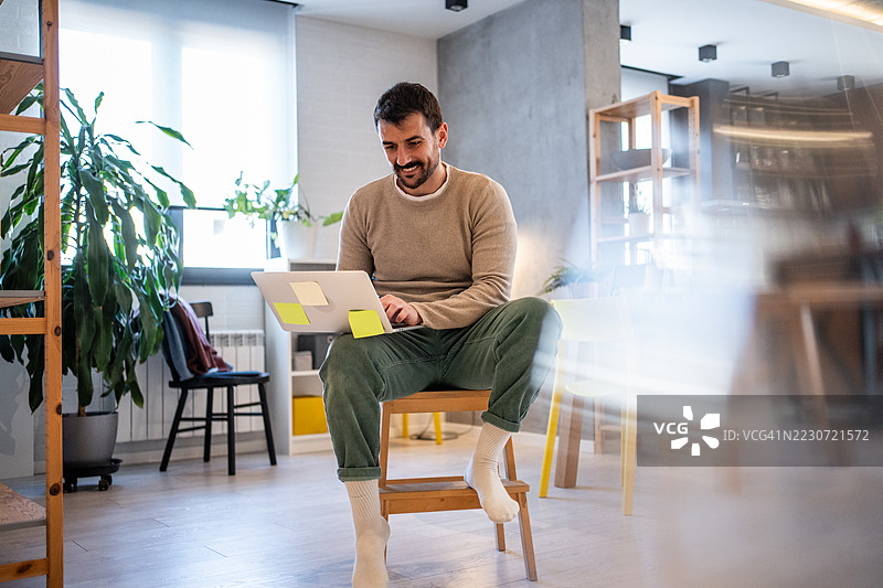 在小木椅上使用笔记本电脑的居家自由职业者图片素材