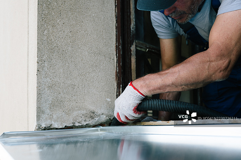 历史别墅的翻新工作：一位工匠正在更换外部金属窗台。图片素材