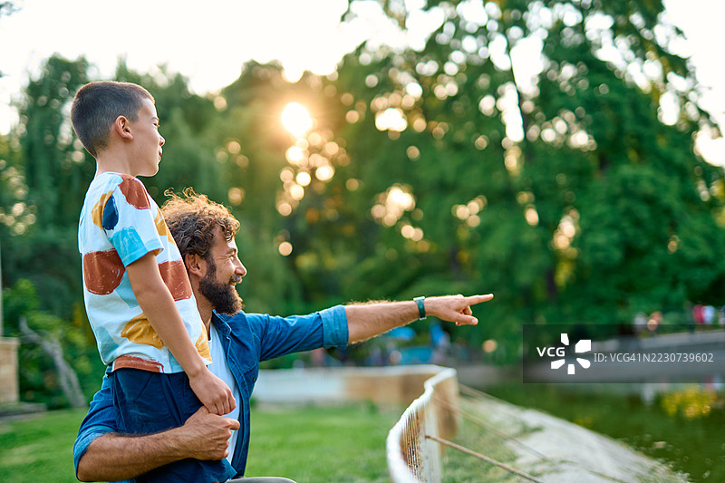 父亲和儿子在公园里享受一天，指着某个有趣的东西。图片素材