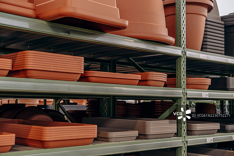 金属货架上堆叠着各种形状和大小的陶瓷、赤陶和塑料花盆图片素材