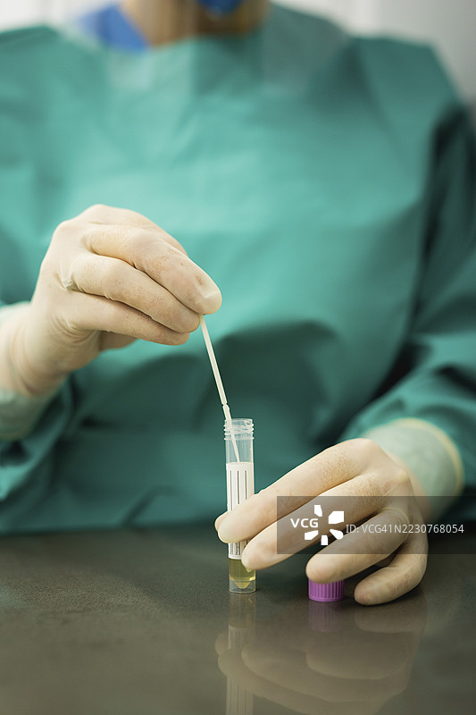 医生将拭子插入试管进行医学分析图片素材