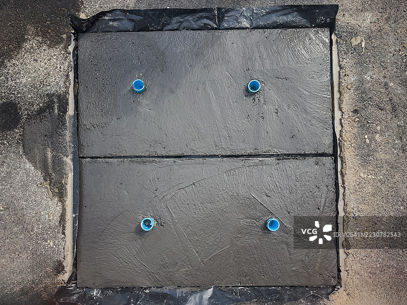 两个新浇筑的混凝土板呈方形，内嵌四根蓝色排水或管道管道。图片素材