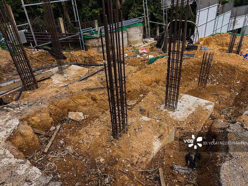 混凝土基础与垂直钢筋嵌入在一个正在进行早期基础工作的活跃施工现场的土壤中。图片素材