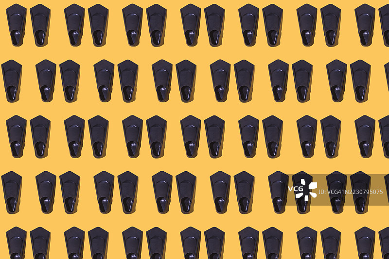 黑色潜水和游泳鳍的图案，背景为黄色。游泳、潜水、比赛、海滩、海洋、度假、休闲、放松和运动。图片素材