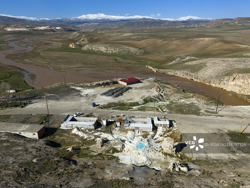 土耳其东安纳托利亚阿勒省迪亚丁地区，穆拉特河沿岸，俯瞰地热温泉、丘陵地貌及黑色山丘，河岸有建筑图片素材