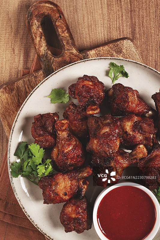 多汁的炸鸡块，配上辛辣的蘸酱，摆放在质朴的木桌上图片素材
