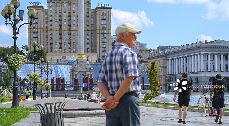 老年男子在基辅市独立广场上眺望，背景是斯特拉纪念碑。图片素材