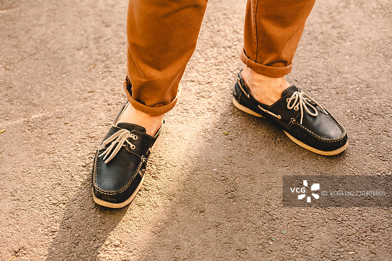 夏天，一名穿着船鞋的男子站在城市街道上图片素材