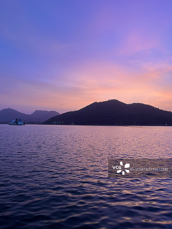 印度乌代布尔日落时分的宁静湖泊与剪影山丘图片素材