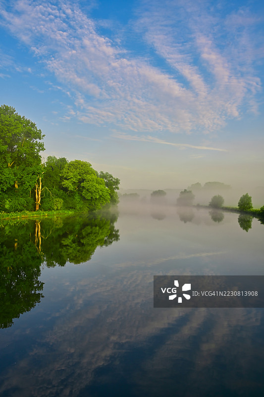 黎明时分，雾气弥漫的河流映照着树木和天空，德国伊瑟尔隆图片素材