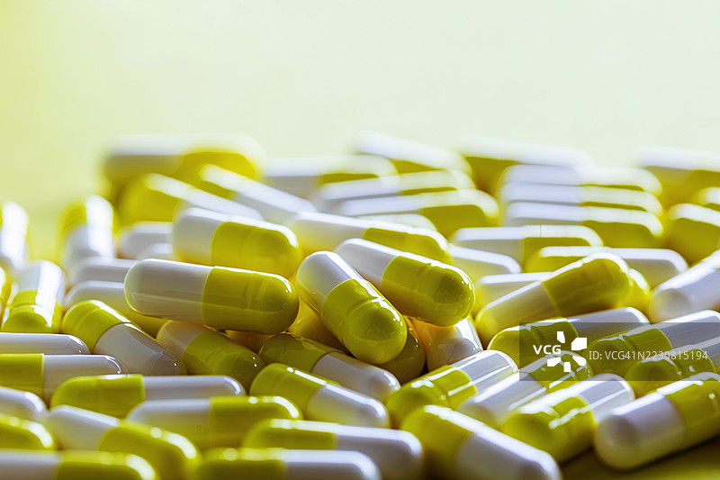 黄色和白色药丸在黄色背景上堆成一堆图片素材