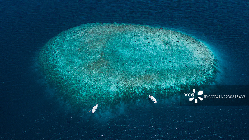 珊瑚礁的鸟瞰图，四周环绕着深蓝色的海洋图片素材