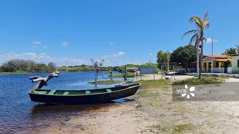 宁静的河边场景，船只和棕榈树在晴朗的蓝天下，巴西图片素材