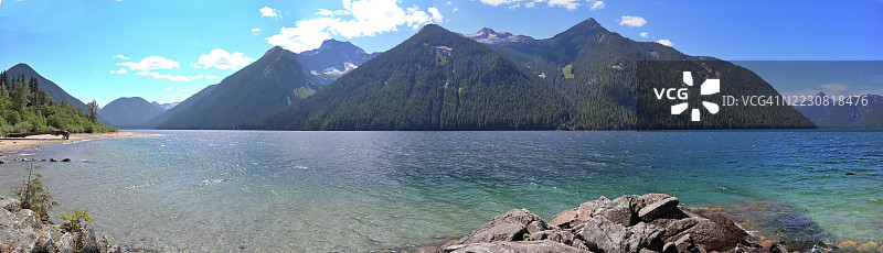 宁静湖泊的全景，四周被雄伟的山脉环绕，蓝天清澈，加拿大图片素材
