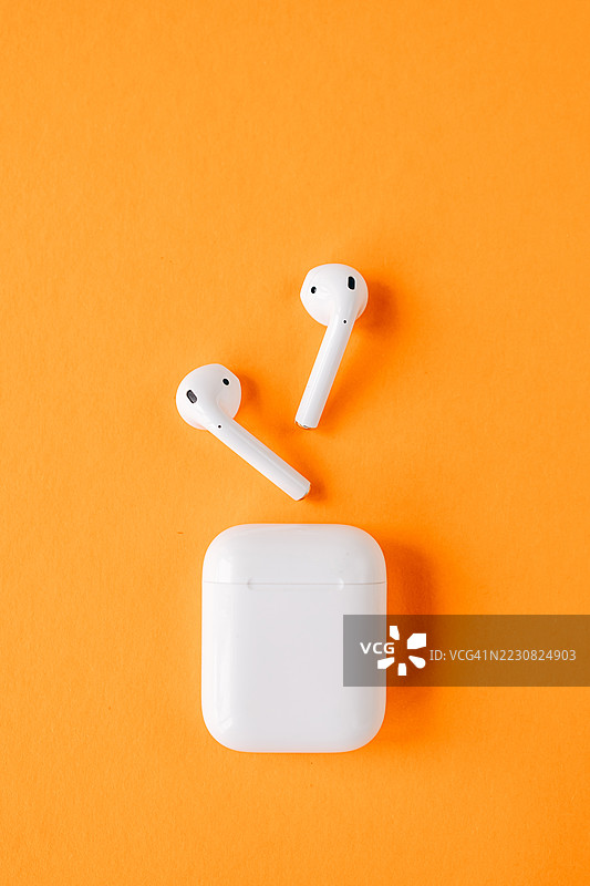 橙色背景上的无线蓝牙耳机图片素材