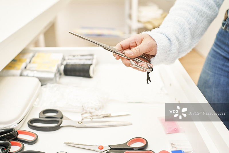女裁缝从抽屉里拿出缝纫剪刀和缝纫工具图片素材