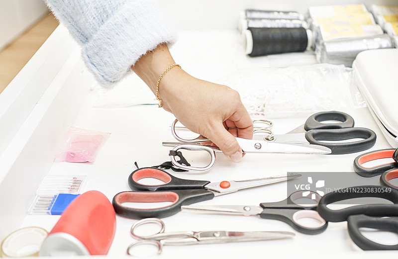 女裁缝从装满缝纫工具的抽屉中拿出剪刀图片素材