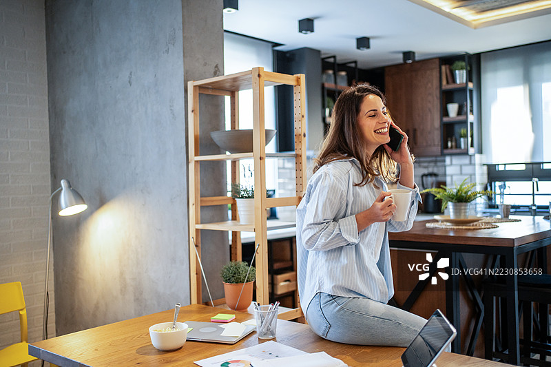 在家工作的自由职业者一边喝咖啡一边打电话图片素材