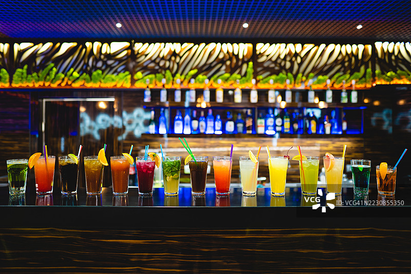 五彩缤纷的鸡尾酒排成一排放在酒吧台上图片素材