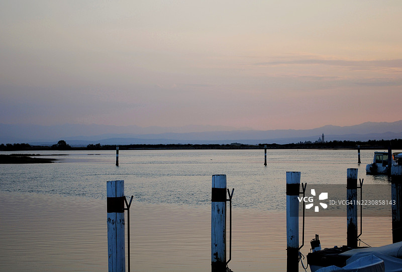 宁静的日落映照在平静的海面上，远处是山脉，意大利格拉多图片素材
