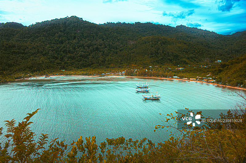 宁静的海湾与船只和郁郁葱葱的山丘，印度尼西亚塔鲁桑Koto XI图片素材