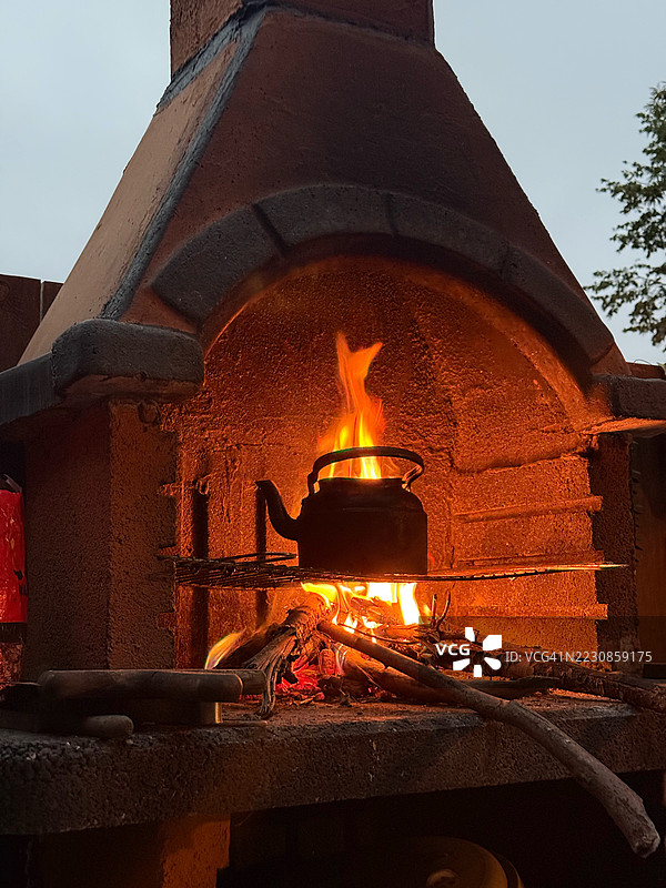 乡村风格的户外壁炉，配有水壶和燃烧的木材图片素材