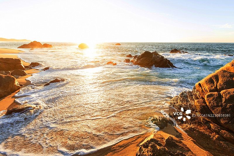 美国亨廷顿海滩岩石海滩上的金色日落图片素材
