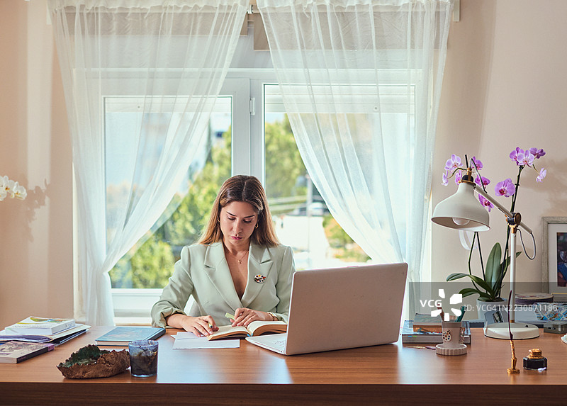 一位女性在家中的书桌上进行研究。图片素材