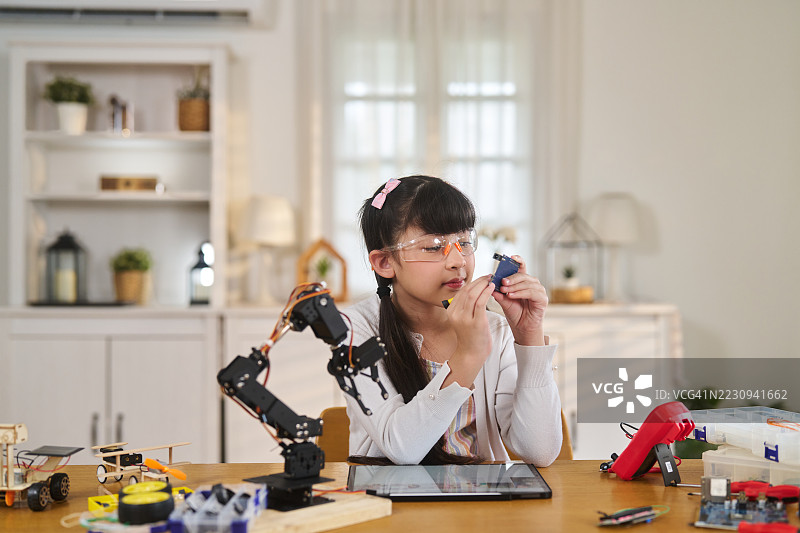 女孩在家中戴着安全眼镜组装机器人图片素材