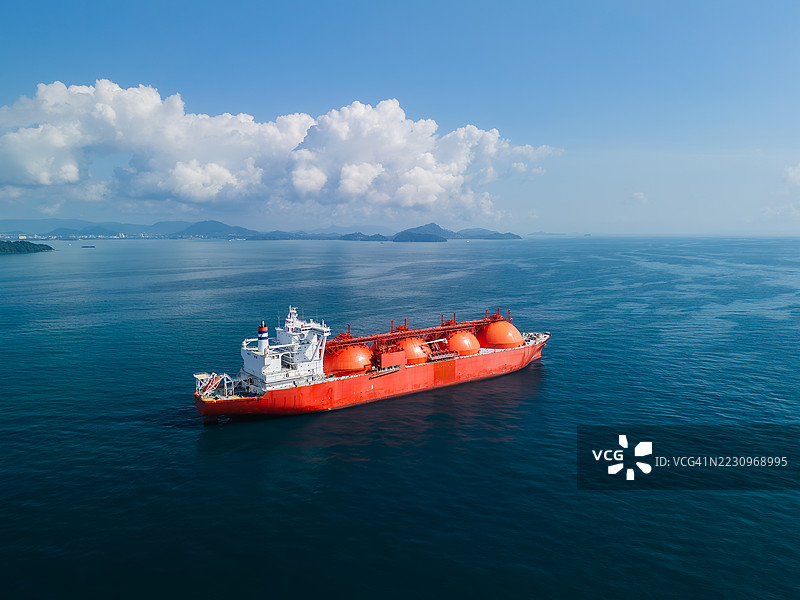大型红色液化天然气（LNG）油轮在开阔水域航行，运输球形气体容器。图片素材