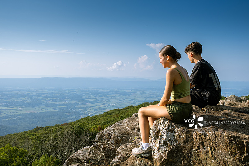 青少年兄妹坐在山脊上欣赏风景图片素材