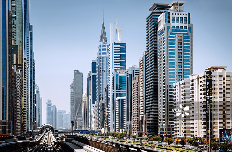 现代列车在谢赫扎耶德路上穿行，背景是迪拜城市天际线图片素材