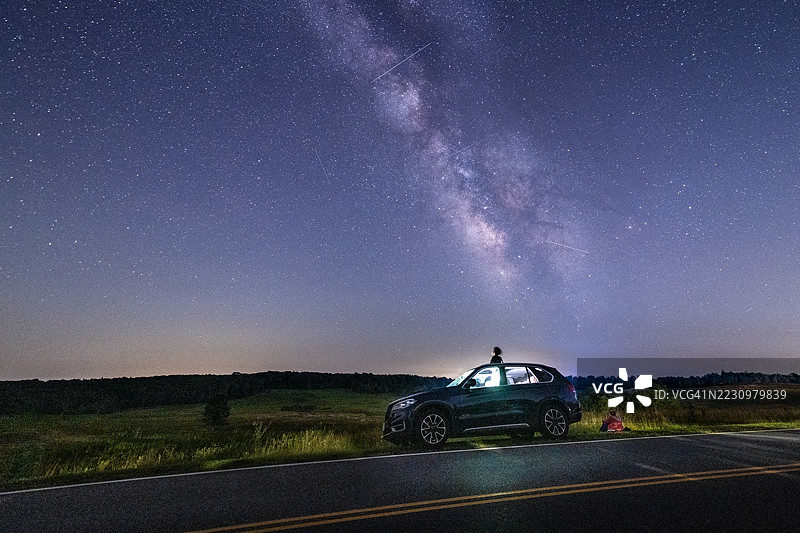 少年男孩从汽车天窗探出头，仰望星空。图片素材