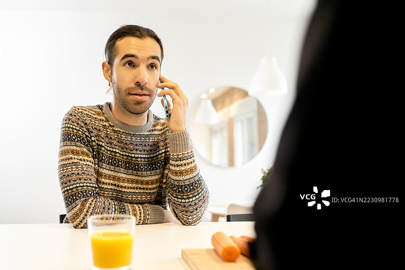 男人在厨房吃早餐时用智能手机通话图片素材