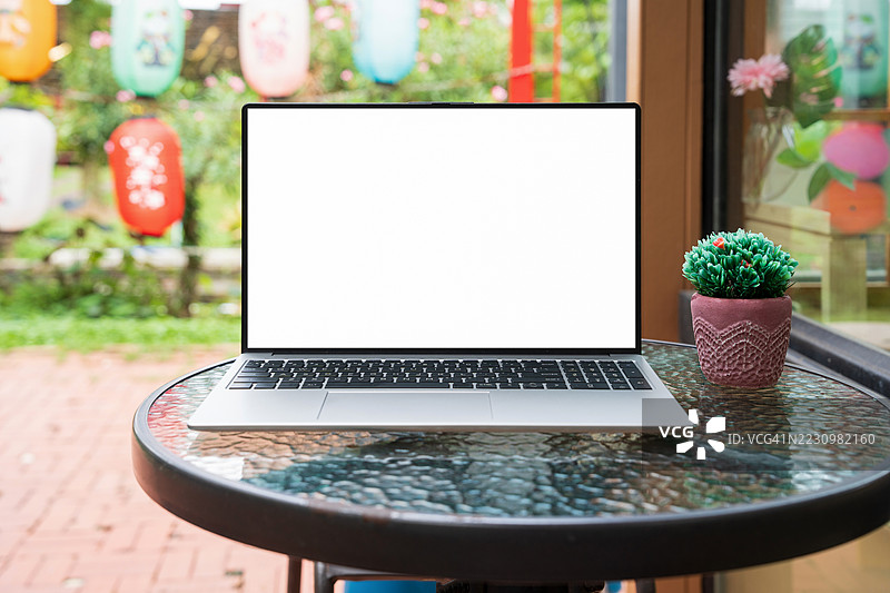 咖啡馆背景下桌子上的笔记本电脑空白屏幕。咖啡店桌子上的笔记本电脑空白屏幕，背景模糊。图片素材