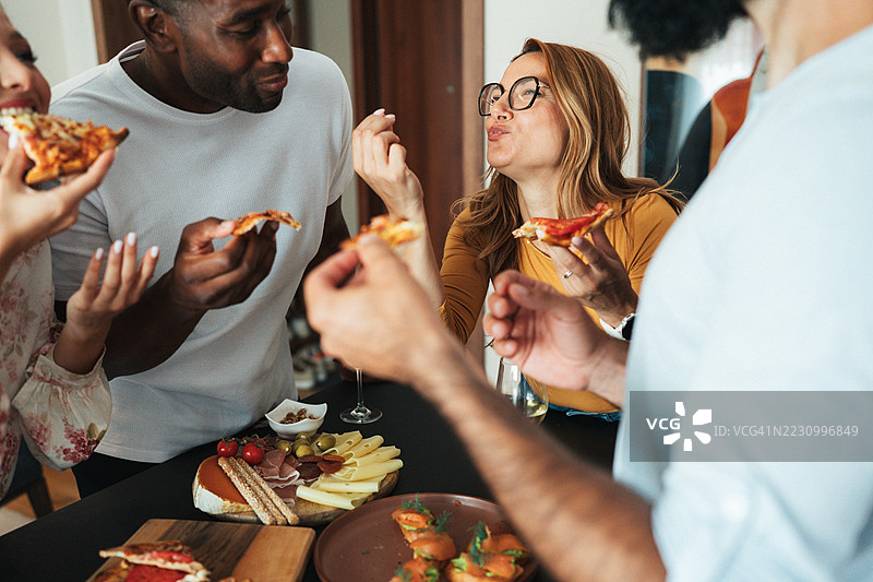 一群朋友在轻松的家庭聚会上享受比萨和葡萄酒图片素材